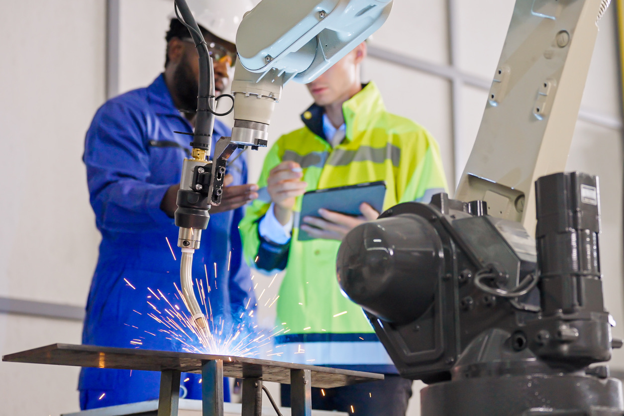Technicians operating a robotic welding cell